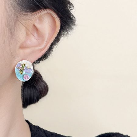 Detailed view of a single dragonfly stud earring showcasing the intricate floral and enamel work.