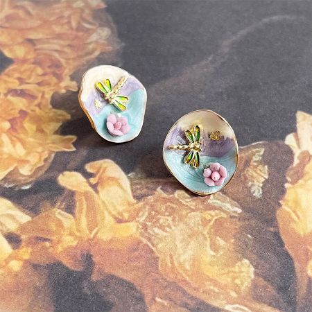 A pair of the dragonfly and flower earrings displayed to show their unique, artistic style.
