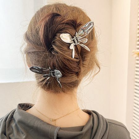A woman with a bun hairstyle adorned with two delicate dragonfly-shaped hair clips.