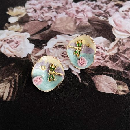 Close-up on the intricate details of the dragonfly and rose design on the stud earrings.