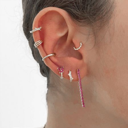 A collection of huggie earrings styled on an ear for inspiration.