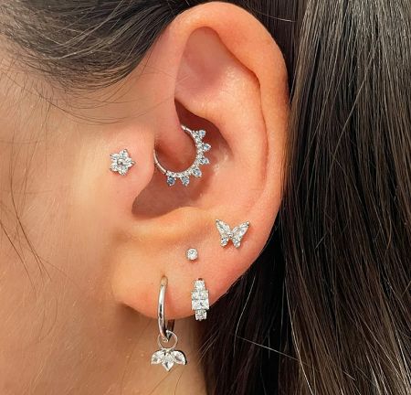 A model showcasing how the 925 Sterling Silver Huggie Earrings can be styled with other ear piercings for a fashionable look.