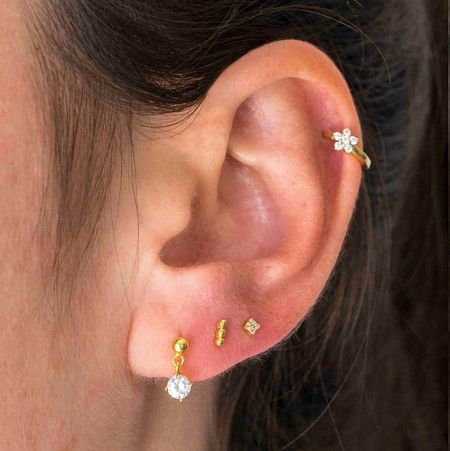 Close-up view of the gold huggie hoop earrings with cubic zirconia on an ear.