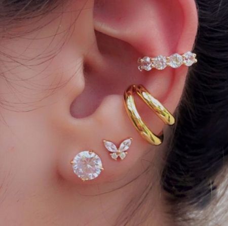 Close-up view of the gold mini earring collection on a model's ear, displaying the intricate details and sparkle.