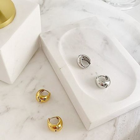 Lifestyle display of both gold and silver teardrop earrings on a marble surface.