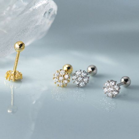 A product showcase displaying three variations of the flower stud earrings in silver and gold finishes.