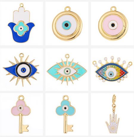 A close-up of nine different evil eye jewelry charms, showcasing intricate details in gold and silver with blue and white enamel.
