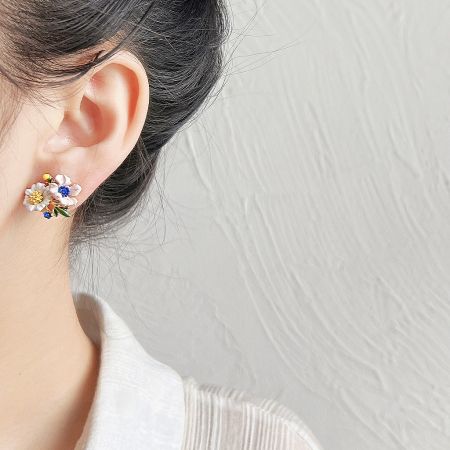 Model wearing a hand-painted enamel flower stud earring.