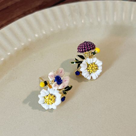 Close-up of two asymmetrical floral stud earrings.