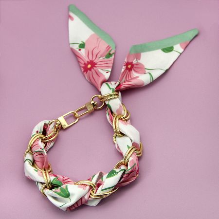 Pink floral braided phone strap with a bunny ear design and gold hardware.