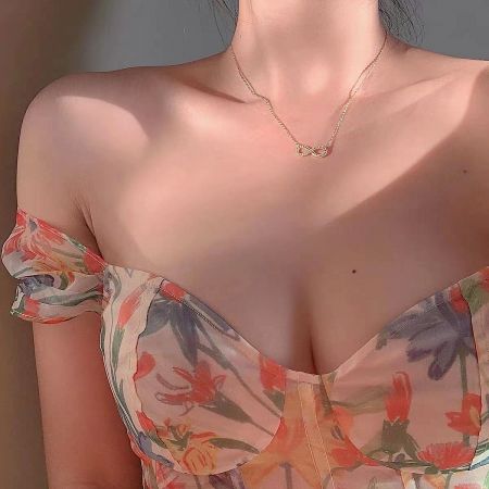 Model wearing the gold infinity necklace with a floral top, showcasing its collarbone length.