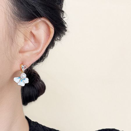 A model showcasing the elegant 14k gold plated enamel flower earring with a pearl center.