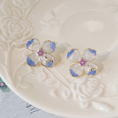 Product shot of the enamel flower earrings on a decorative plate.
