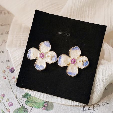 Close-up of the flower stud earrings with blue accents on a display card.