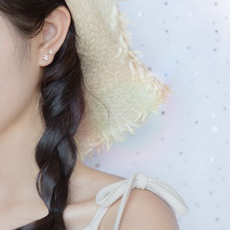 Model wearing the delicate S925 silver small flower stud earrings to show scale.