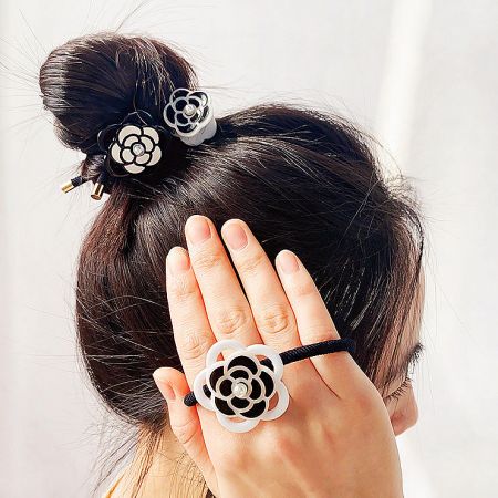A collection of black and white camellia flower hair ties and clips displayed together.