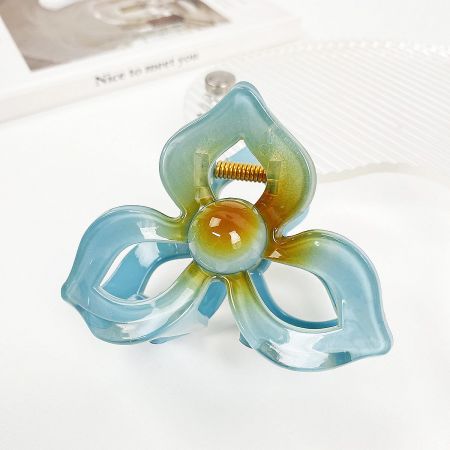 A multi-colored plumeria hair clip featuring shades of blue, green, and yellow.