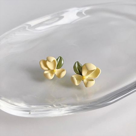The yellow enamel flower earrings displayed on a clear dish to show their craftsmanship.