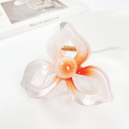 Close-up of a frangipani flower hair clip with a beautiful white and orange gradient design.