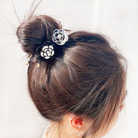 Two flower-shaped hair clips stylishly placed in a hair bun.