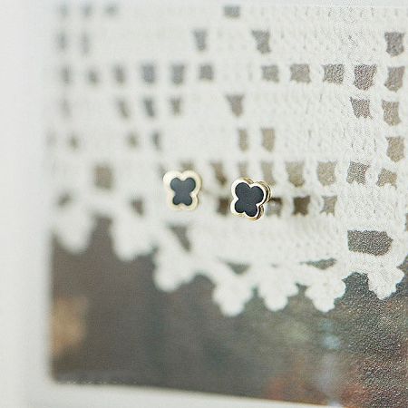 Elegant black enamel butterfly earrings with gold trim, displayed on a decorative white surface.