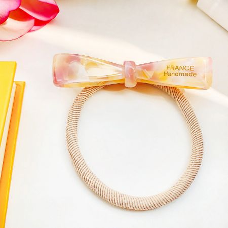 An elegant beige handmade bow hair tie from France, showing detailed craftsmanship.