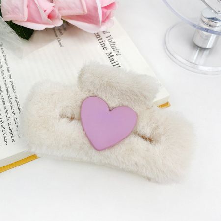 A soft, fuzzy hair clip featuring a sweet pink heart accent.