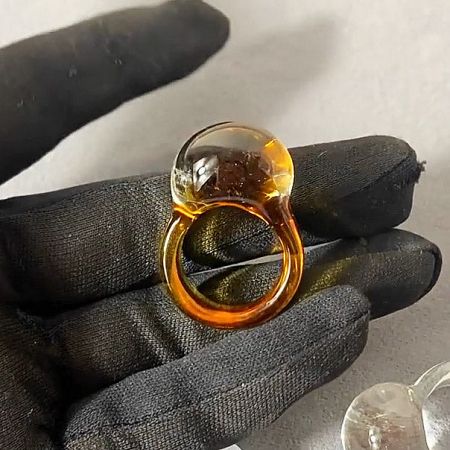 The handmade glass ring in a warm orange-yellow tone, highlighting its artisanal quality.