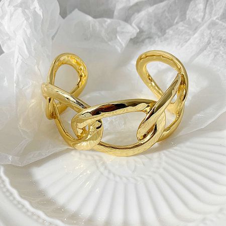 A gold cuff bracelet with a modern, abstract design.