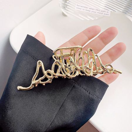 Detailed shot of the abstract gold hair clip, highlighting its unique shape.