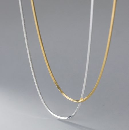 Top-down view of the flat snake chain necklaces in both gold and silver, showing their sleek and modern design.