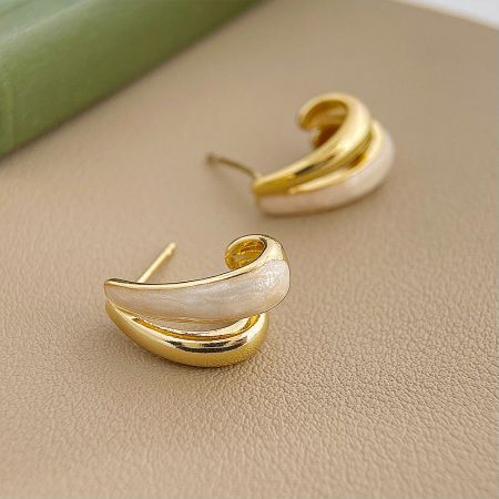 A pair of gold and white earrings with a unique curved design from the 5-pair set.