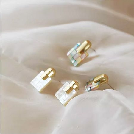 Three pairs of mosaic stud earrings showcasing different color patterns including gold and white.