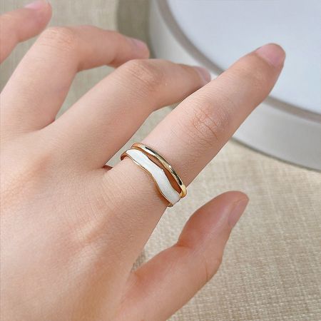 Close-up of the gold and white enamel wavy band ring.
