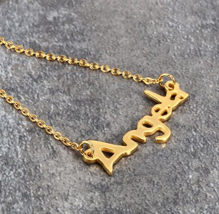 Example of a custom 'Aries' zodiac name necklace in gold plating.