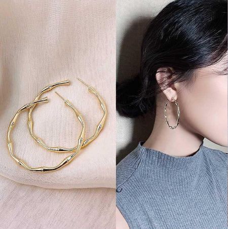Model wearing the bamboo-inspired gold hoop earrings to show scale and style.