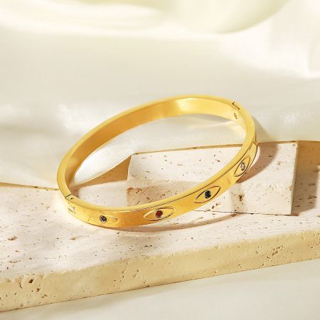 Close-up of a gold bangle from the set, highlighting the intricate evil eye motif and zircon details.