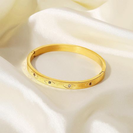 A gold bangle from the set featuring sparkling gemstone accents.
