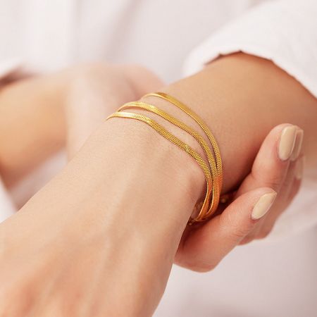 Model's wrist adorned with the elegant set of 5 gold snake chain bracelets.