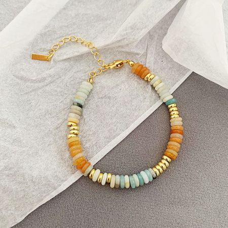 Close-up of a stackable boho bracelet with orange, white, and gold natural stone beads.