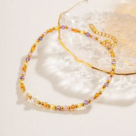 A gold beaded anklet with various multicolored stones, highlighting the craftsmanship of the set.