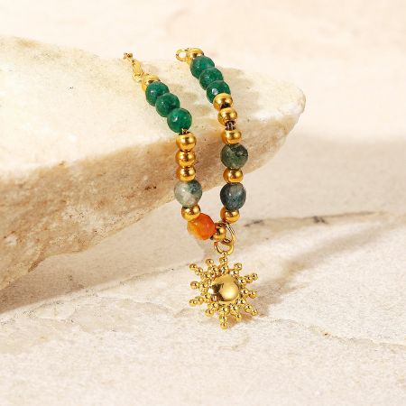 Close-up of the matching gold beaded bracelet with multi-colored stones and a sun charm.