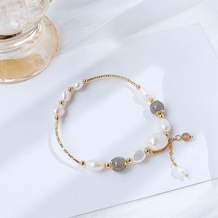 A stylish 14k gold plated bracelet with a mix of white, gray, and pink beads, showcasing its delicate design.