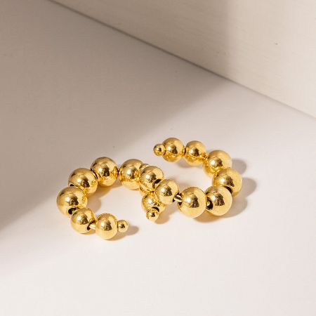 Detailed view of the gold beaded ear cuff's texture.