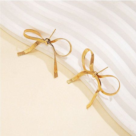 Detailed product shot of the gold bow-shaped earrings with a textured metal finish.