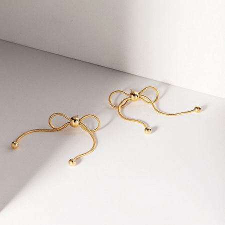 A pair of stainless steel gold knot bow stud earrings on a white background.
