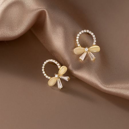 Detailed view of the gold bow earrings showcasing the pale yellow and clear stone accents.