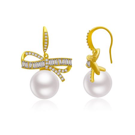 Angled view of the gold bow earrings, highlighting the sparkle of the cubic zirconia stones and the elegant pearl drop.