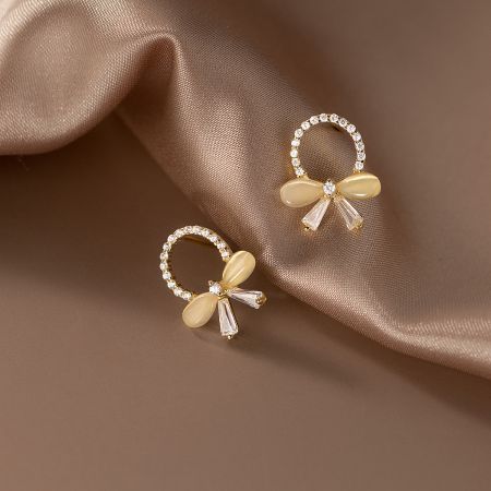 Close-up view of the intricate bow design on the gold-plated sterling silver earrings with cubic zirconia.