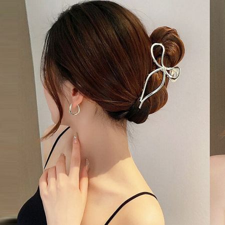 Detailed product shot of a delicate gold bow-shaped hair clip.